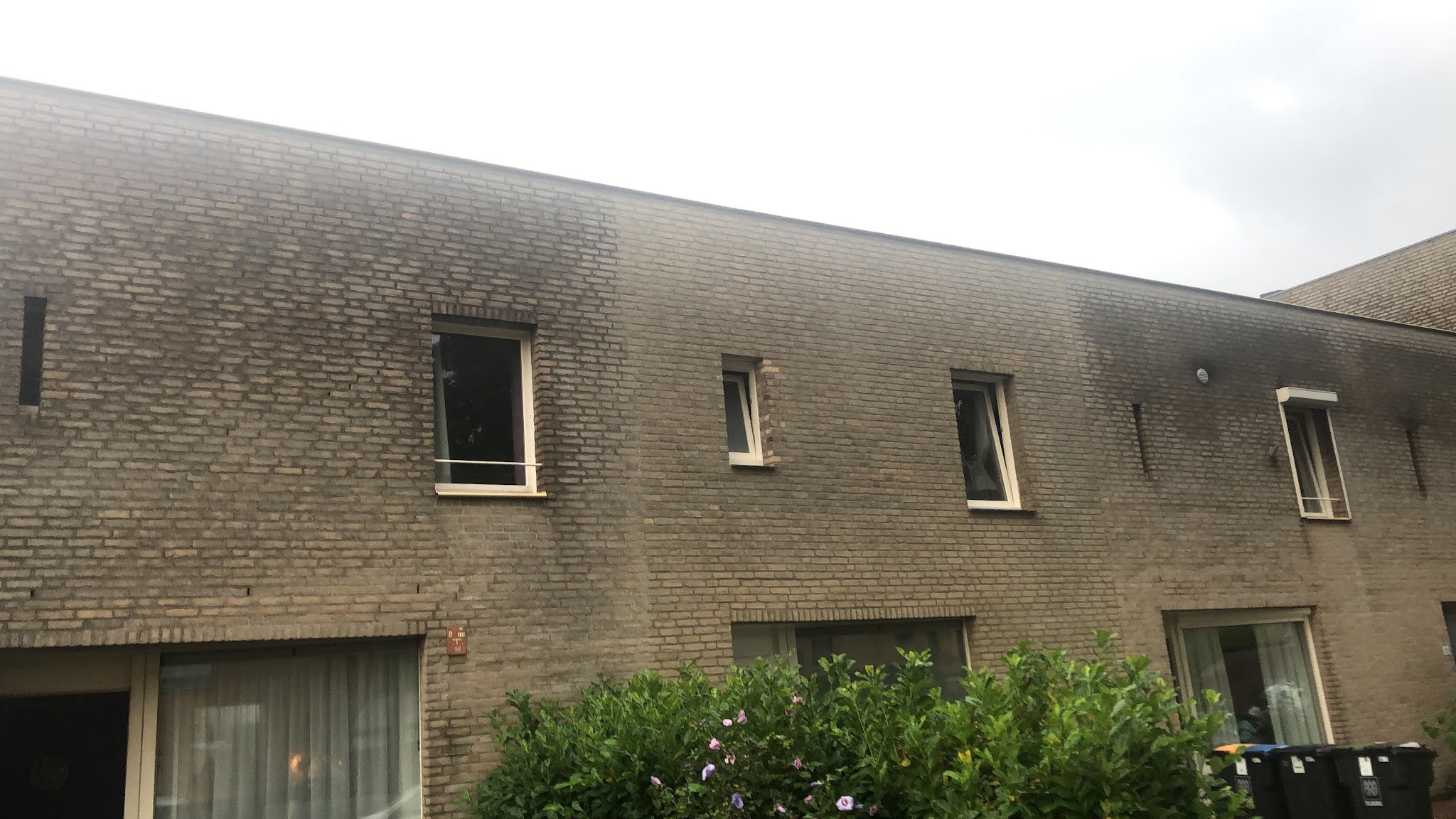 Gevel van een rijtjeshuis met een gereinigd en geïmpregneerd deel naast donker verweerd metselwerk